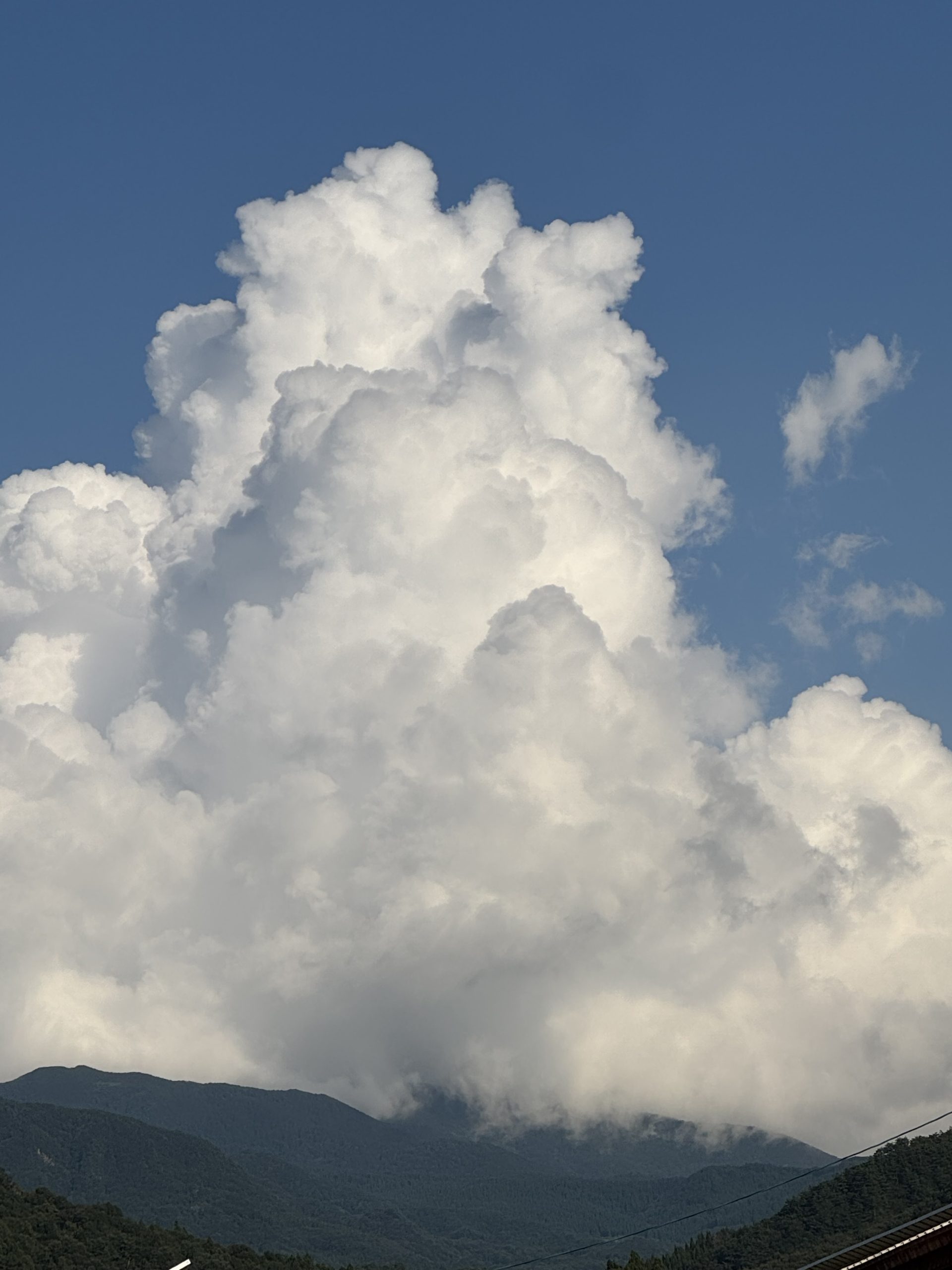 山形県天童市の農場から見た、山の上に立ち上がる入道雲と青空